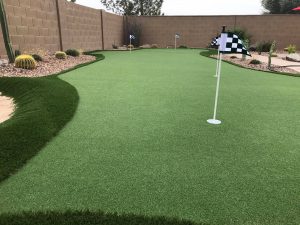 A backyard with a putting green and flag.